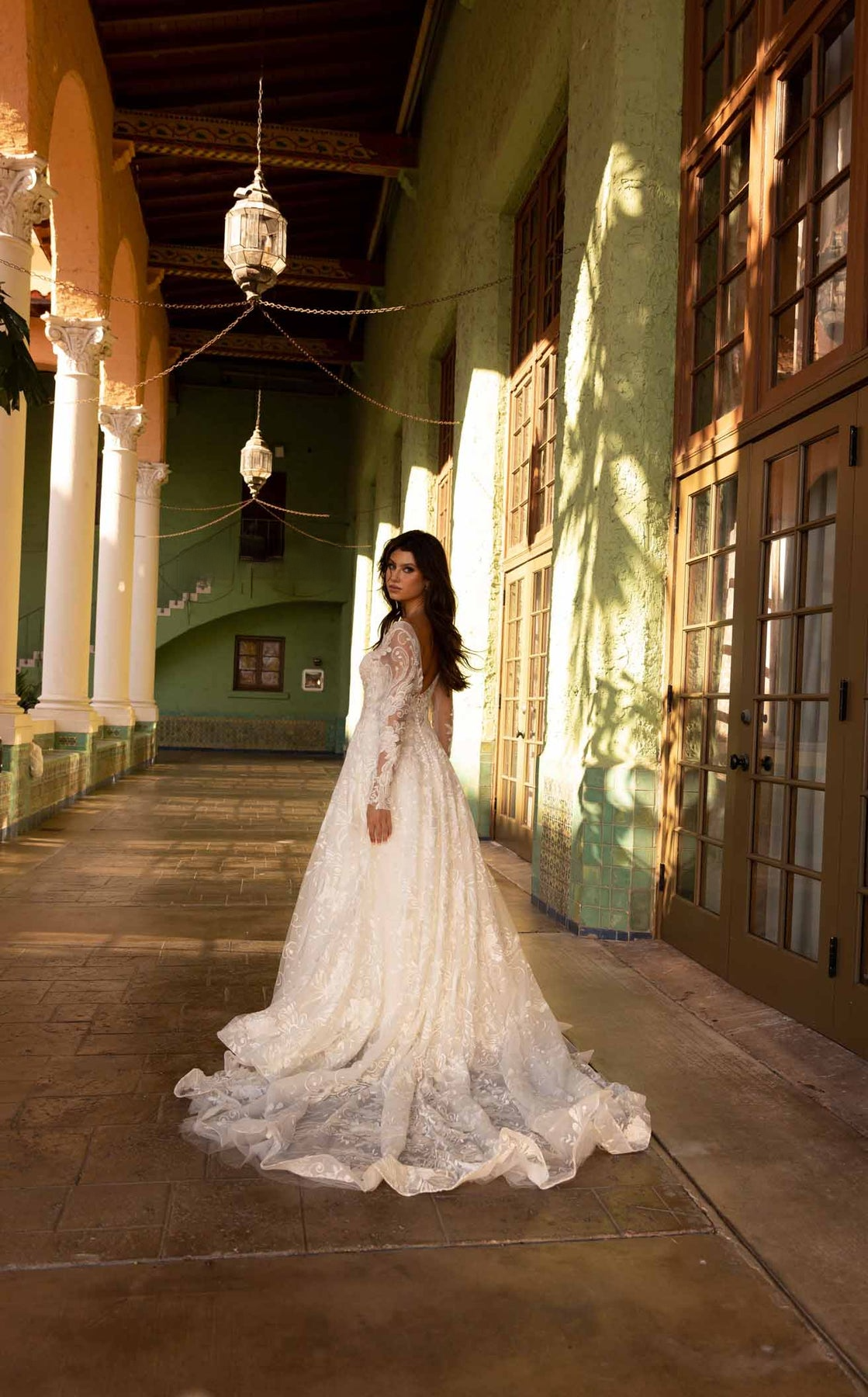 XAYWEAR bridal ball gown with long lace train and sheer long sleeves in elegant hallway