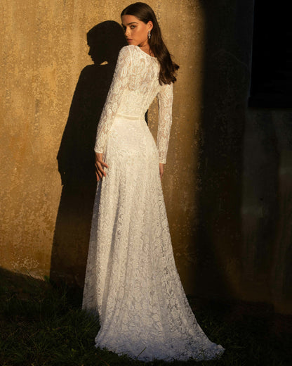 XAYWEAR white bridal gown with long lace sleeves and flowing skirt worn by model standing outdoors