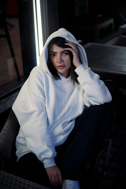 XAYWEAR white hoodie worn by woman sitting outdoors with hood up and relaxed pose
