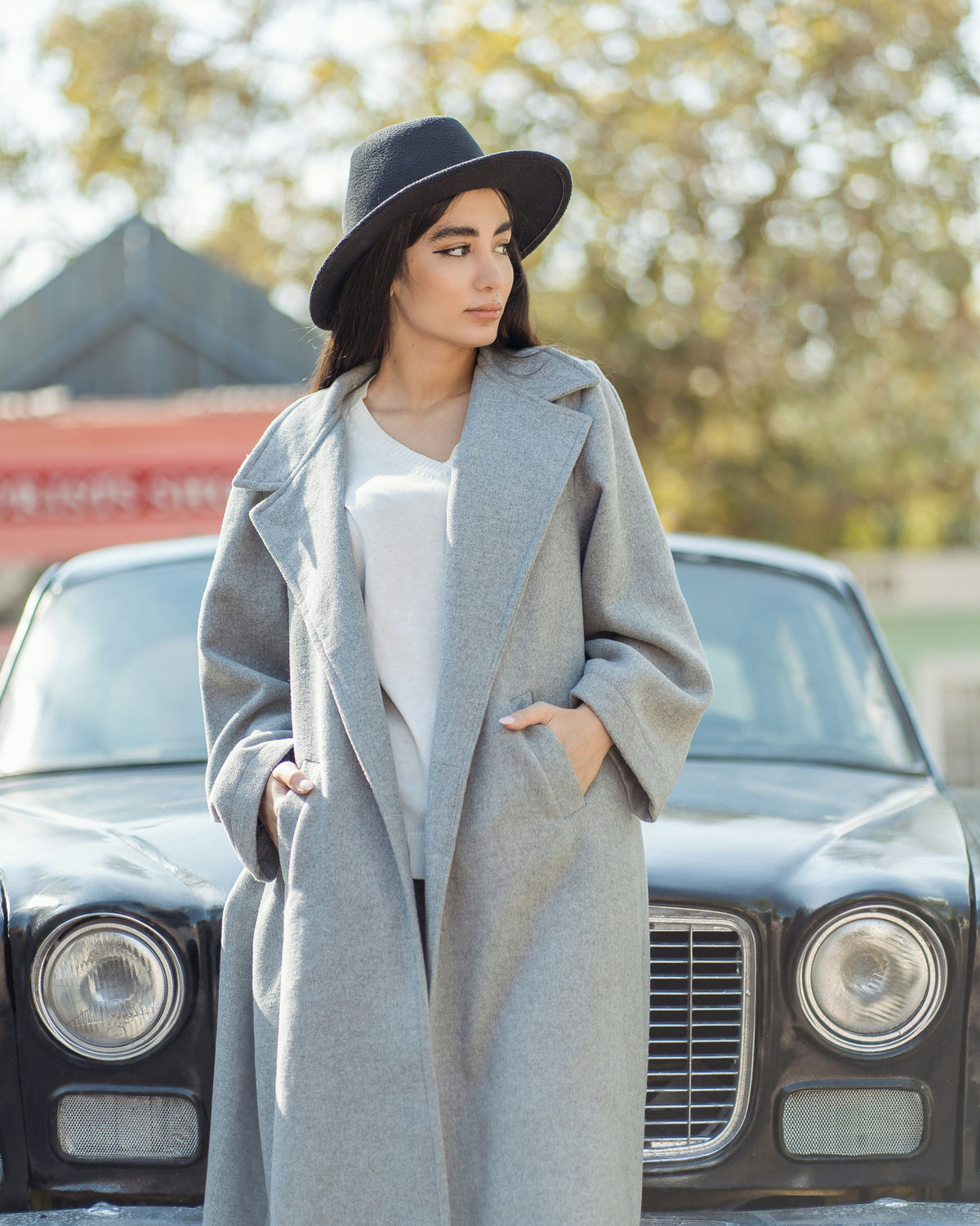 XAYWEAR trendy oversized coat for women in gray, paired with a stylish hat, standing beside a vintage car