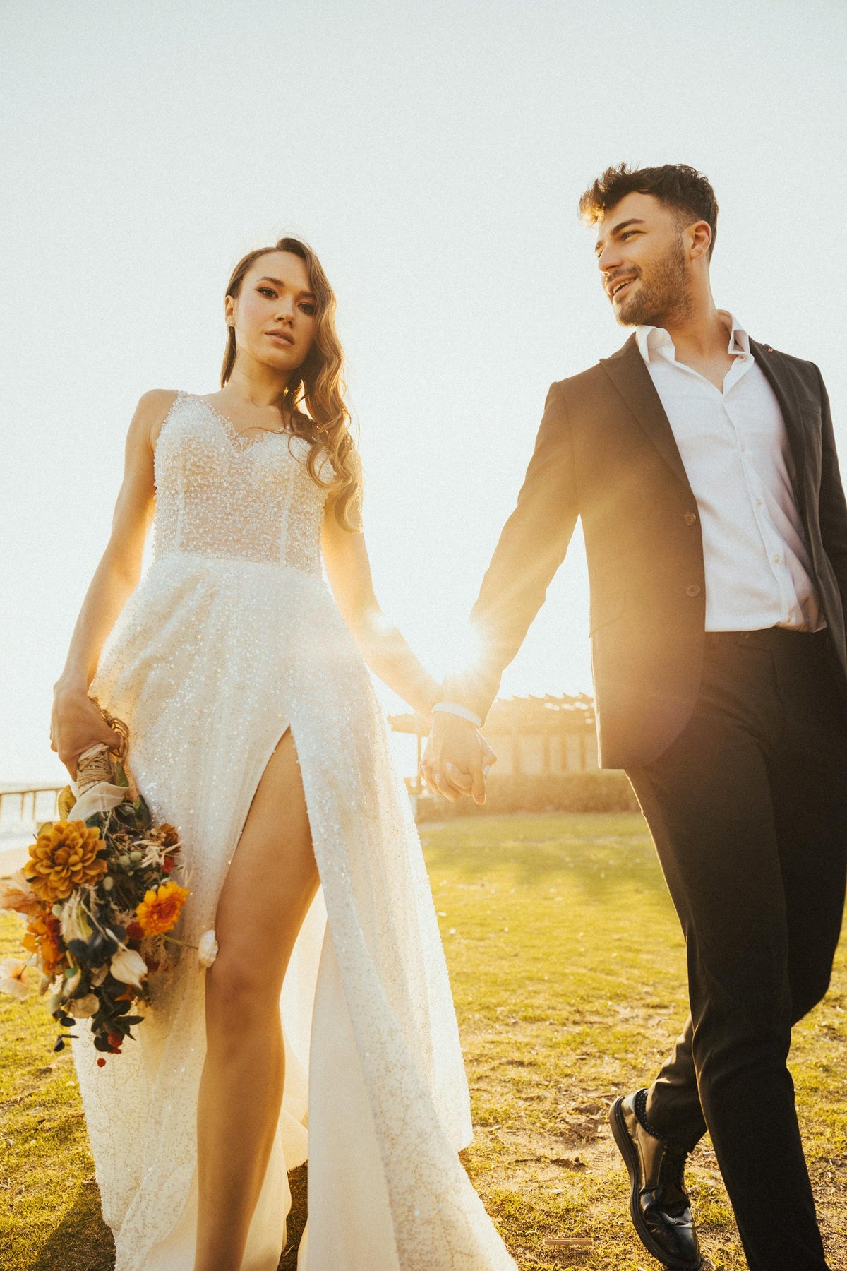 Bride wearing XAYWEAR Wedding Gown with lace details and thigh slit holding bouquet outdoors