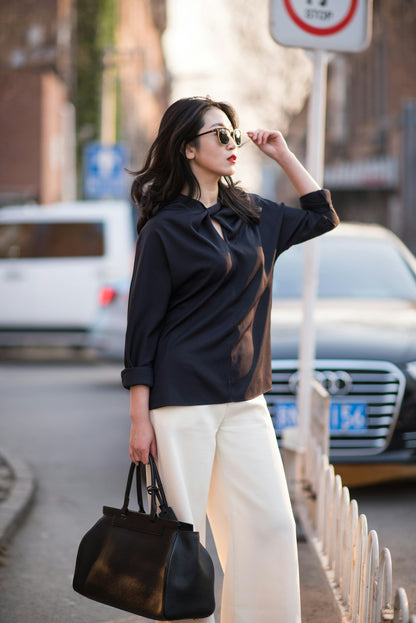 XAYWEAR stylish women outfit with black top and white pants paired with black handbag and sunglasses